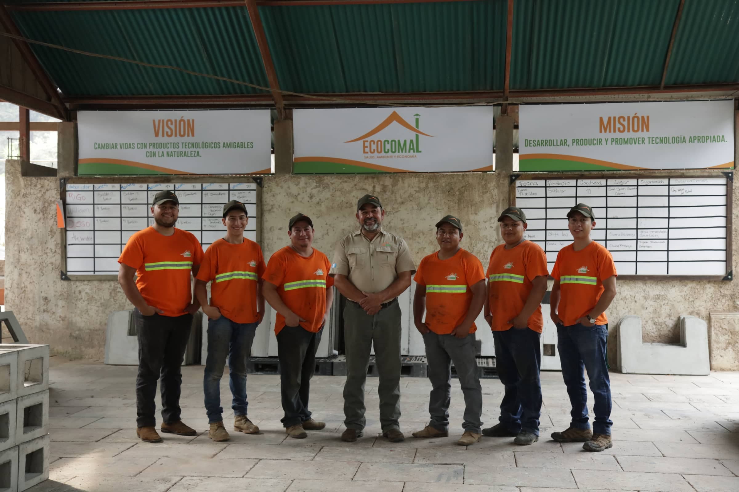 Equipo de producción de Ecocomal frente a los rótulos de visión y misión de la planta